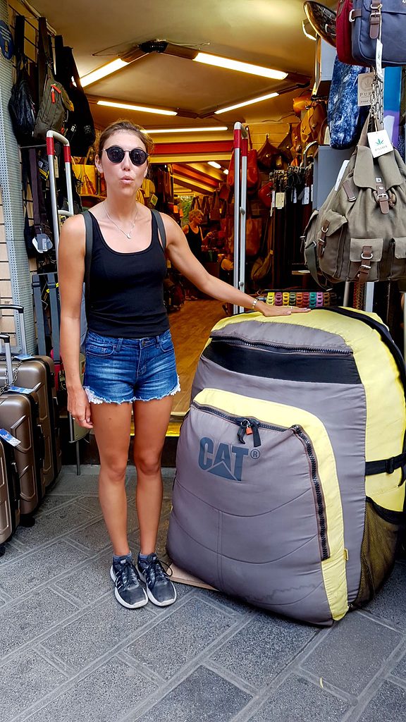 Aly standing next to a giant backpack in Asia while living abroad