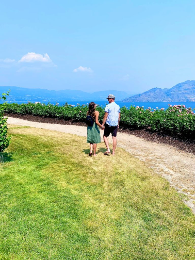 couple walking along lakefront vineyard