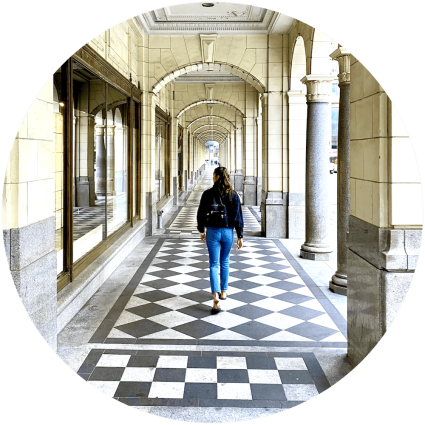 About Us, Aly walking through arched architecture in Calgary